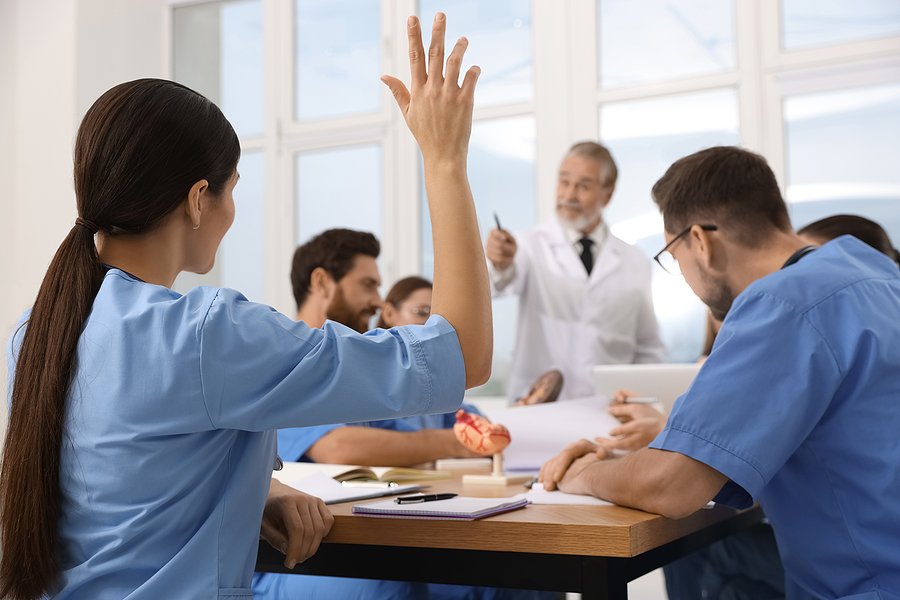 Nursing student in classroom asking professor a question