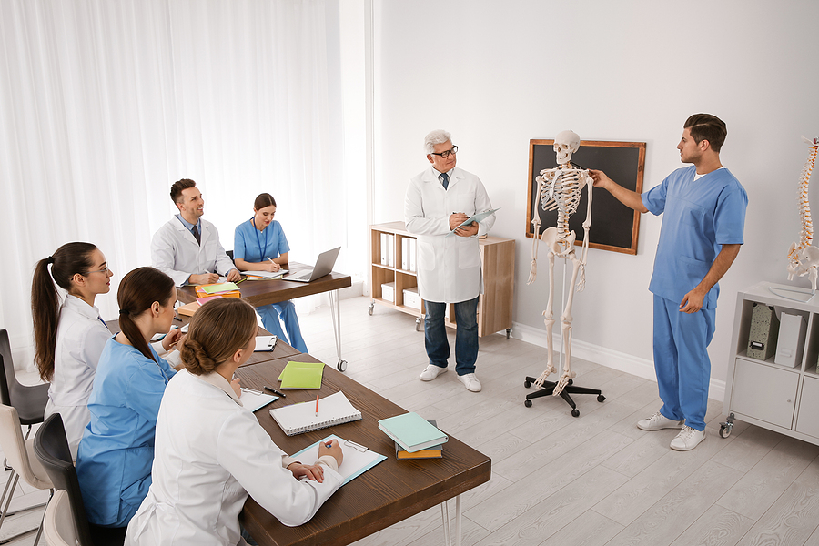 Nurse educator in classroom of students pointing to a model of a skeleton